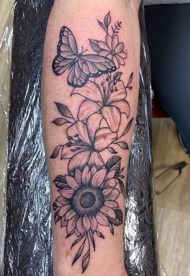 Black and grey butterfly, lilies and sunflower forearm tattoo by Luis Munoz