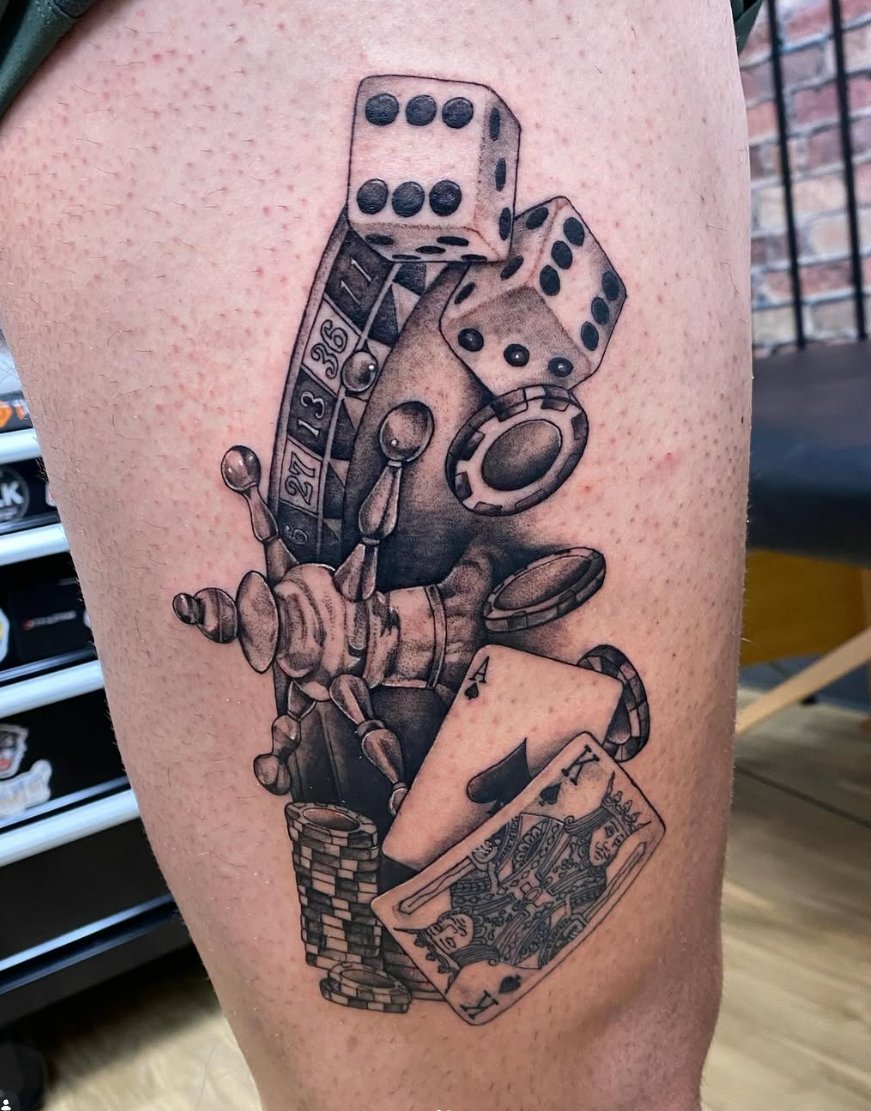 Black and grey casino piece with dice, roulette, chips and cards thigh tattoo by Luis Munoz